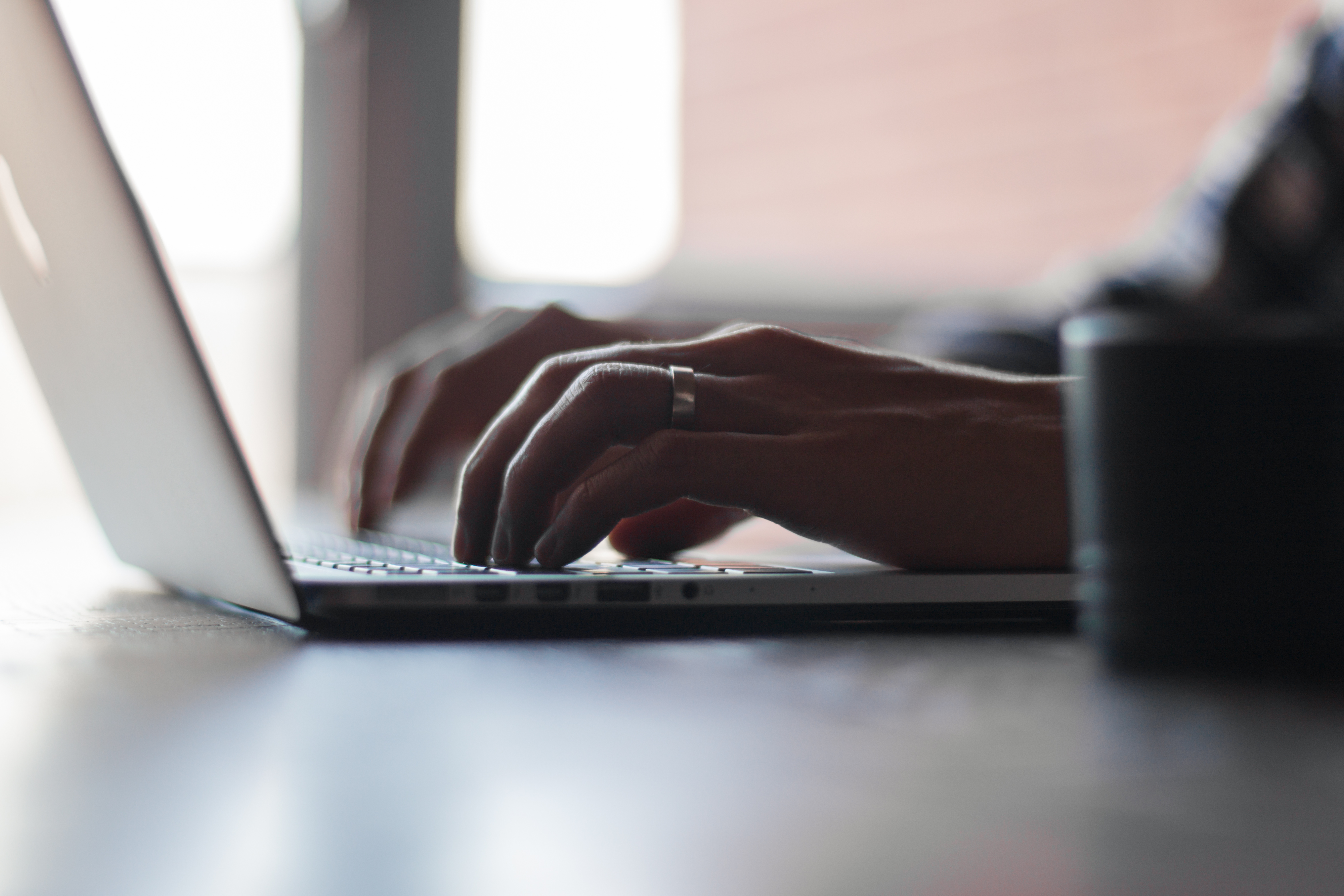 Side view of hands on a laptop keyboard.